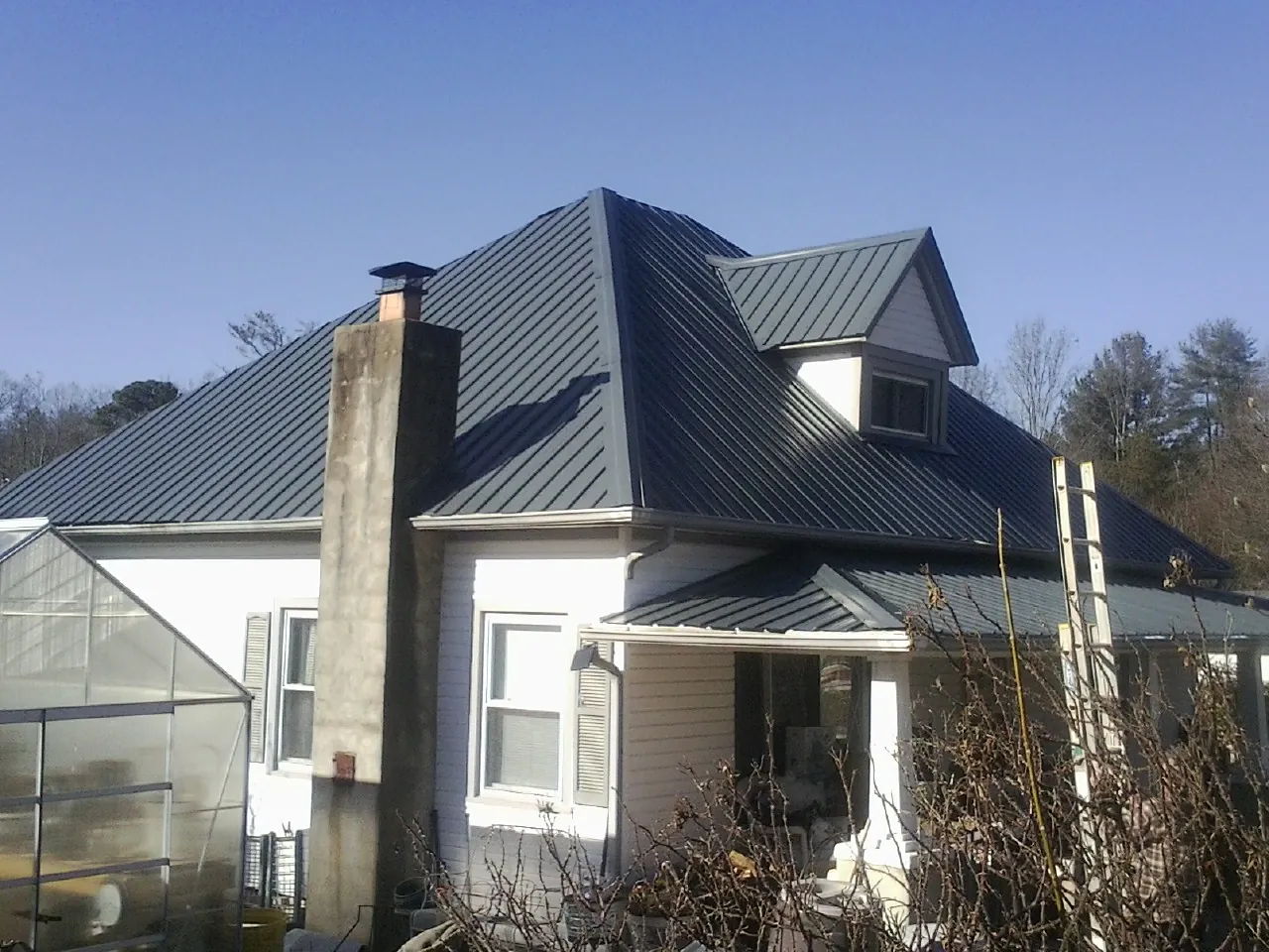Dark blue standing seam metal roof on a white farmhouse with dormer — Slate & Tile Roof Repair by Roofing Brothers in Flanders