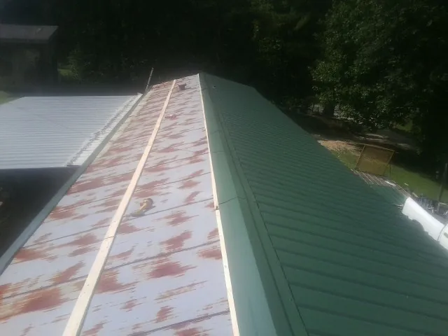Old rusted panels beside newly installed green metal roofing — Wind Damage Roof Repair by Roofing Brothers in Flanders