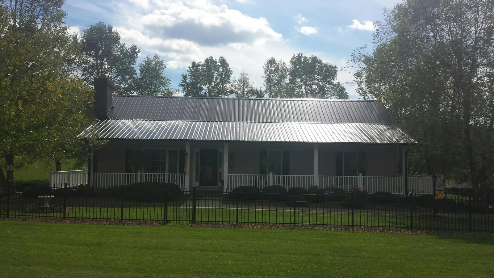 Gray metal roof on a brick ranch with a full width front porch — Gutter Guard Installation work by our crew in Flanders