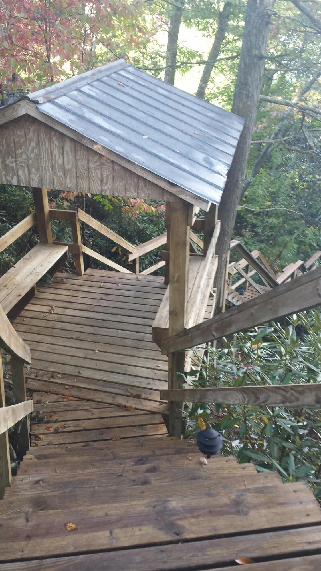 Metal roofed shelter over wooden steps on a wooded walkway — Skylight Repair & Installation work by our crew in Flanders
